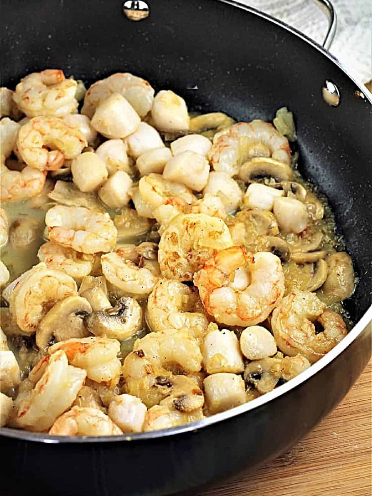 Seafood and scallops sautéed in skillet for coquilles St-Jacques.