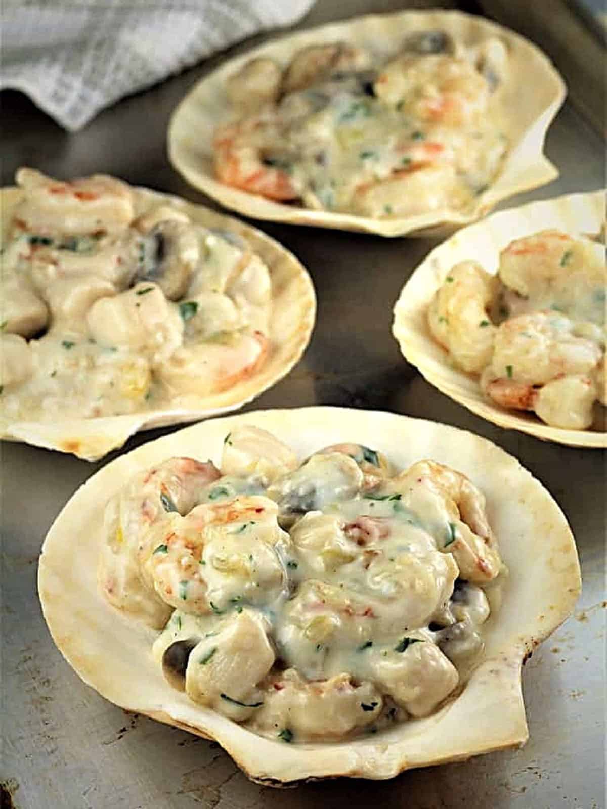 Seafood divided amongst scallop shells for Coquilles St-Jacques recipe.