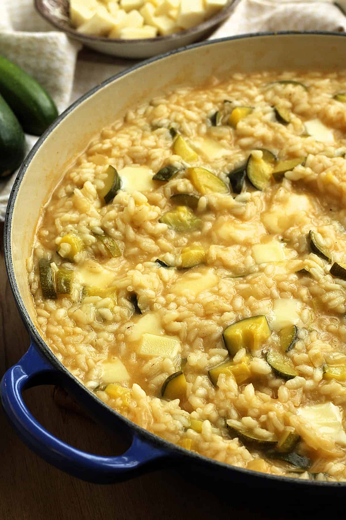 Creamy zucchini risotto with melted scamorza cheese in large sauce pan.