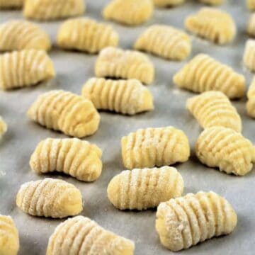 Ricotta gnocchi resting on parchment covered baking sheet.