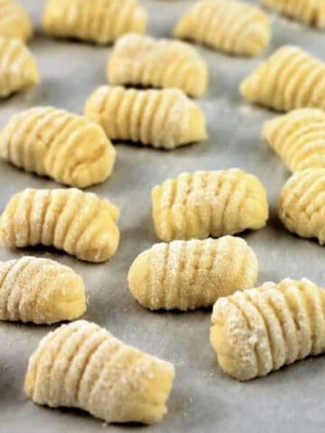 Gnocchi with ricotta resting on baking sheet.