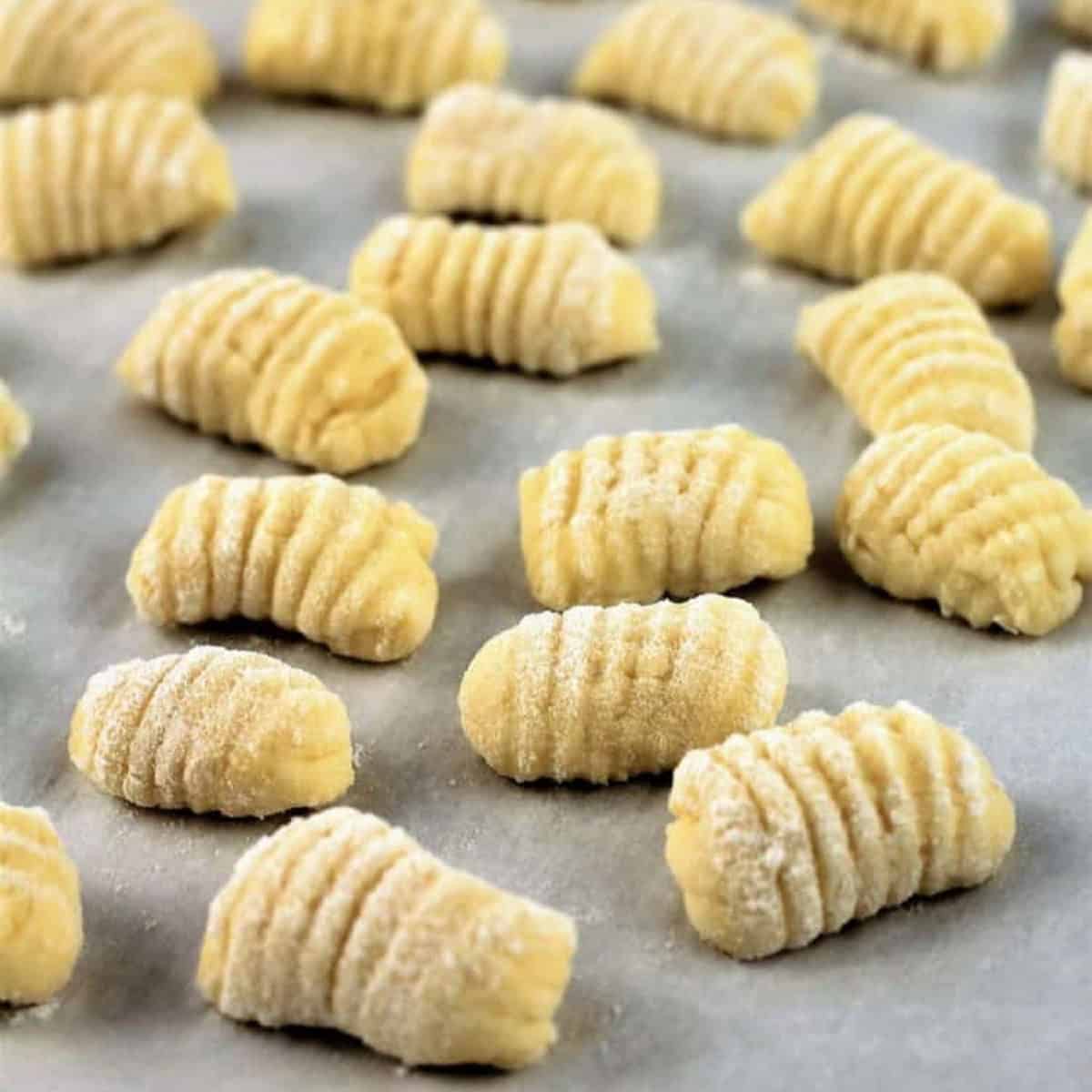 Gnocchi with ricotta resting on baking sheet.