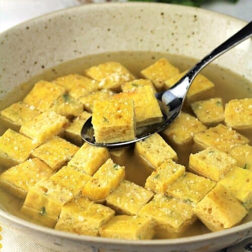 Bowl of zuppa imperial, with frittata squares, spooned.