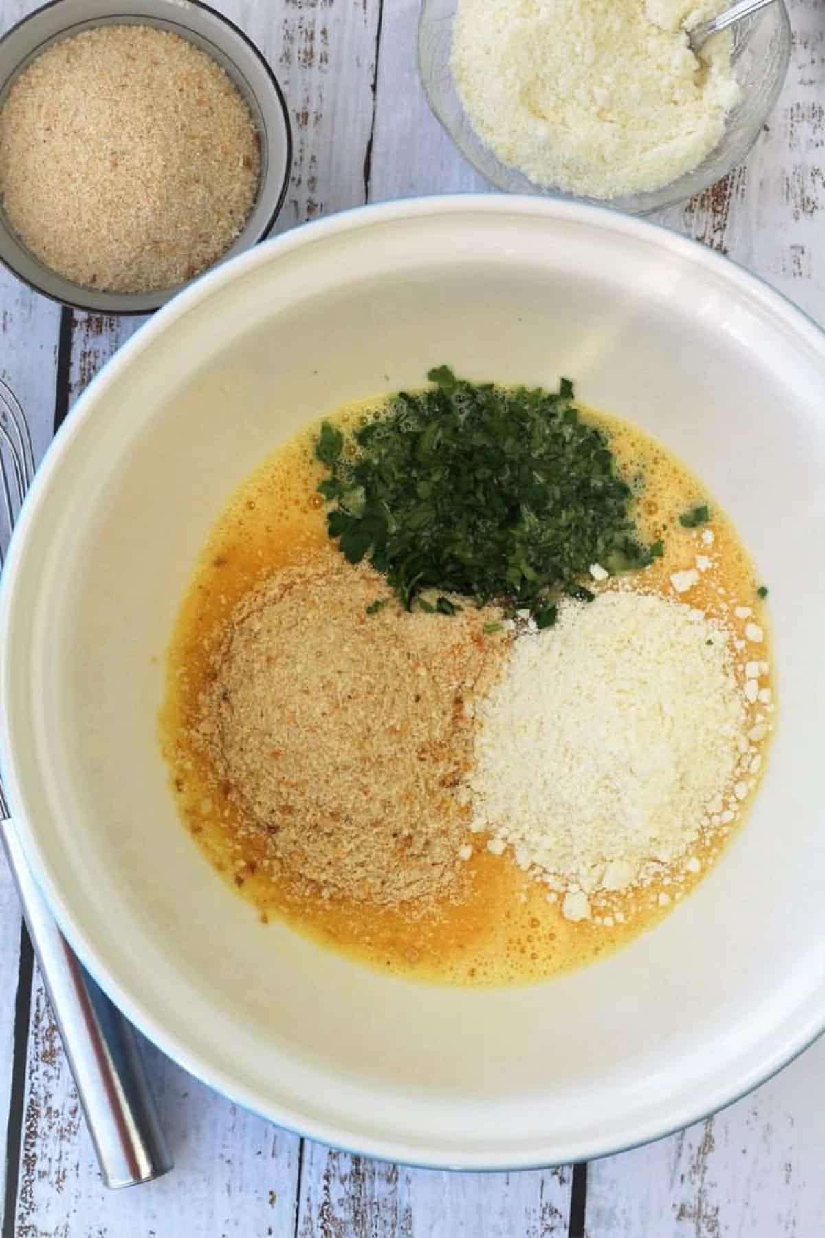 Breadcrumbs, chopped parsley and Parmigiano cheese added to bowl with beaten eggs.