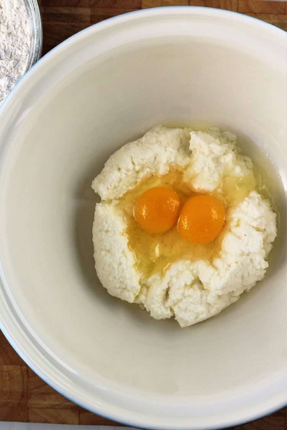 Ricotta and eggs in large bowl for preparing ricotta gnocchi.
