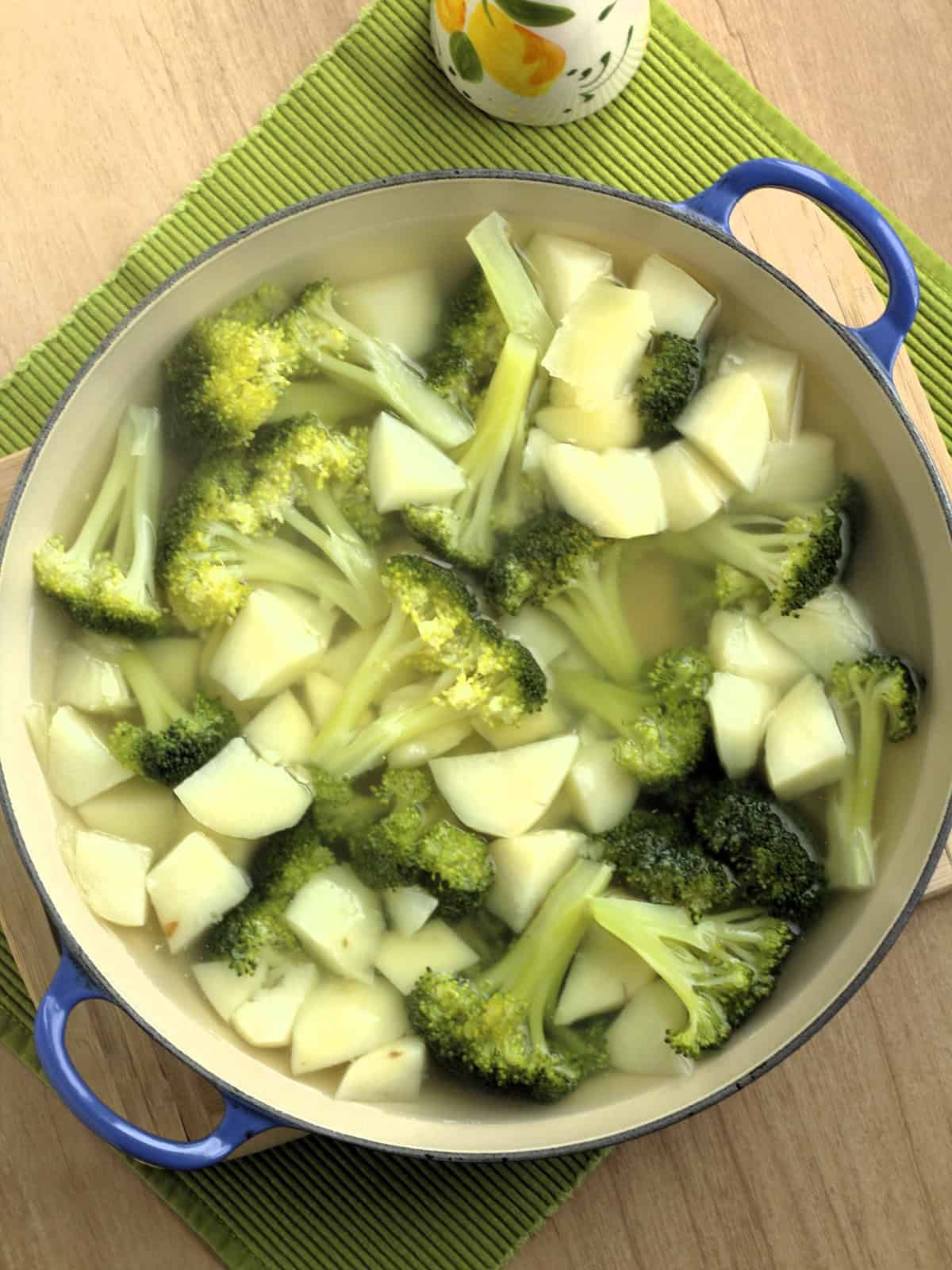 Broccoli florets and cubed potatoes boiling in sauce pan for broccoli potato patties.