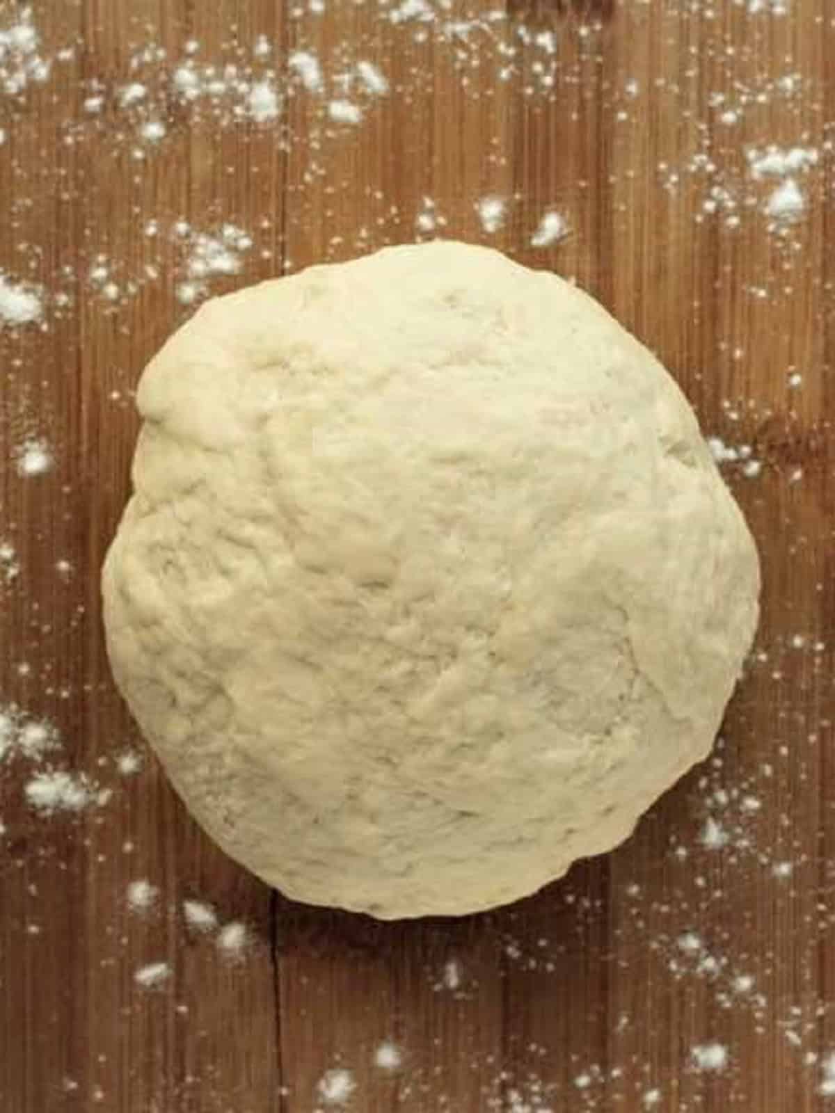 Sfincione dough ball on wood board.