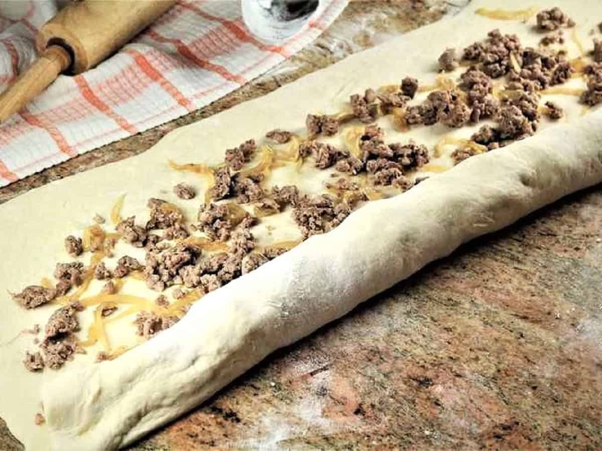 BIgnolati dough filled with onions and sausage rolled up.