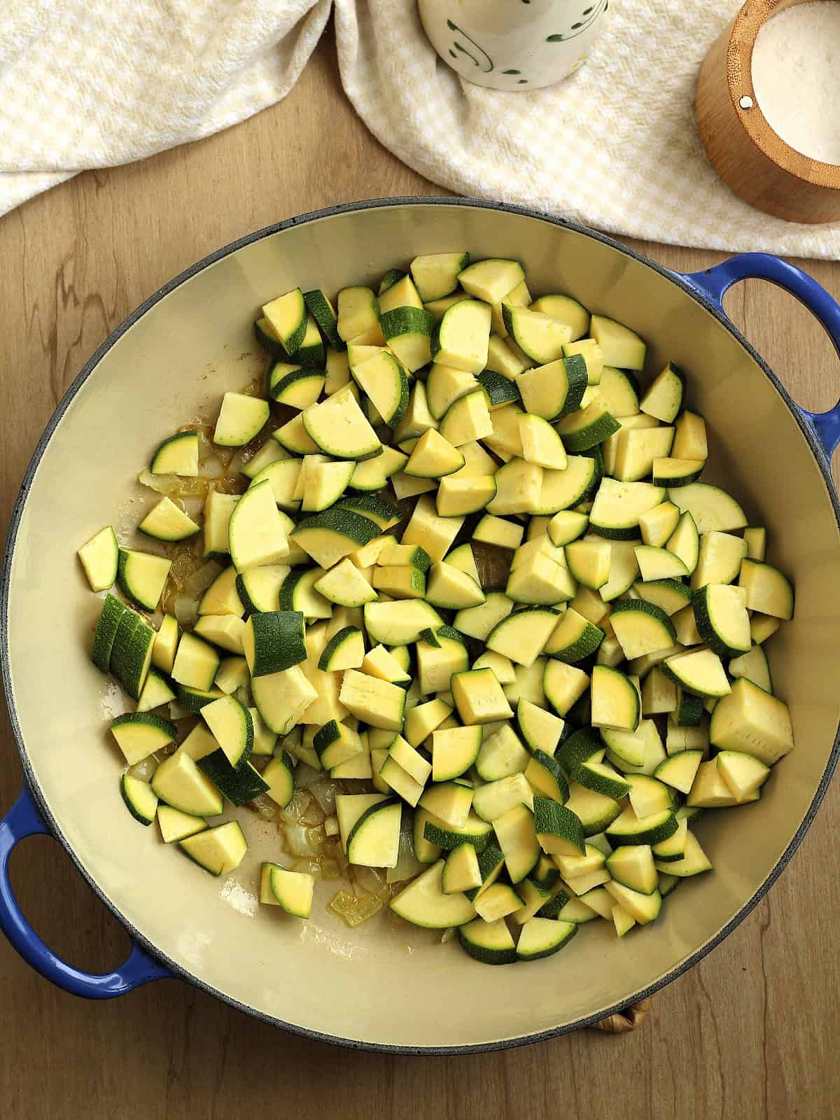 Diced zucchini added to sauce pan with onion for zucchini risotto.