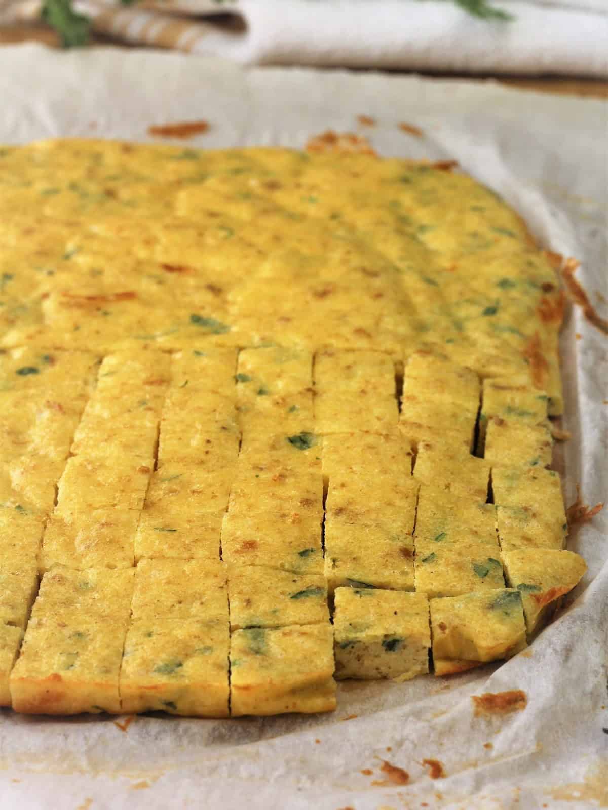 Frittata baked on baking sheet cut into cubes for zuppa imperiale recipe.