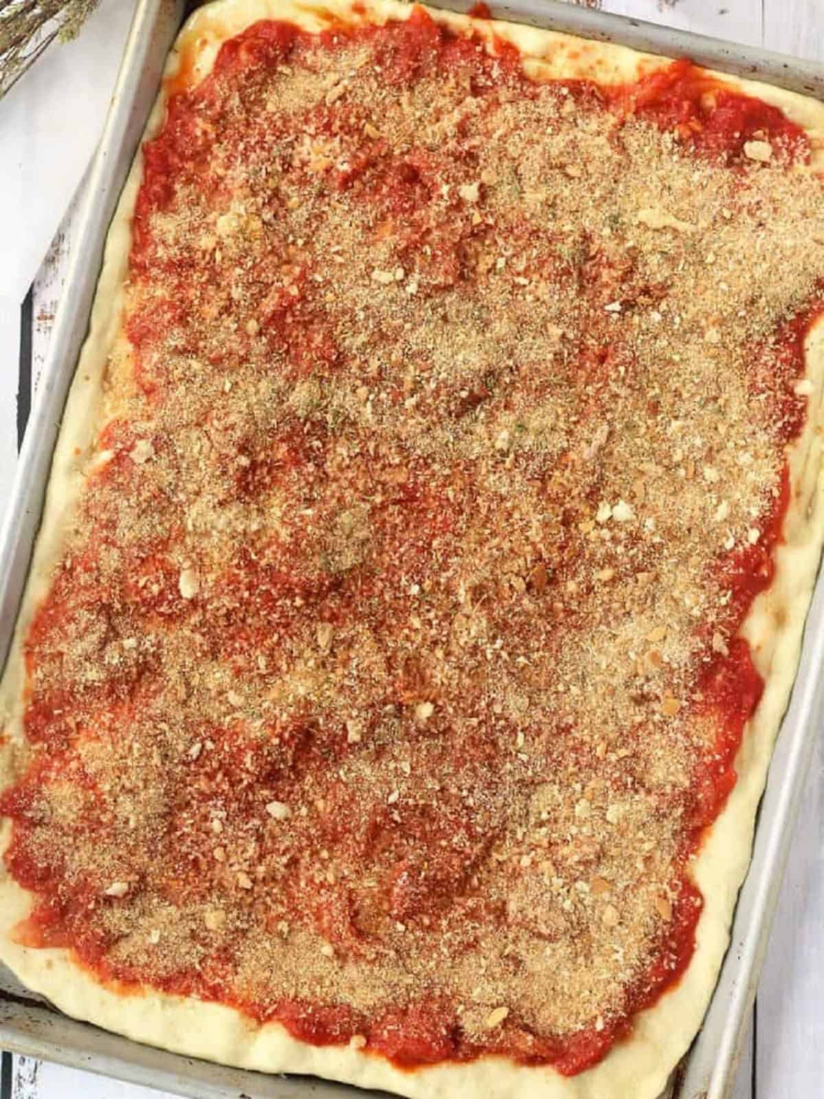 Sfincione dough topped with sauce and crispy breadcrumbs.