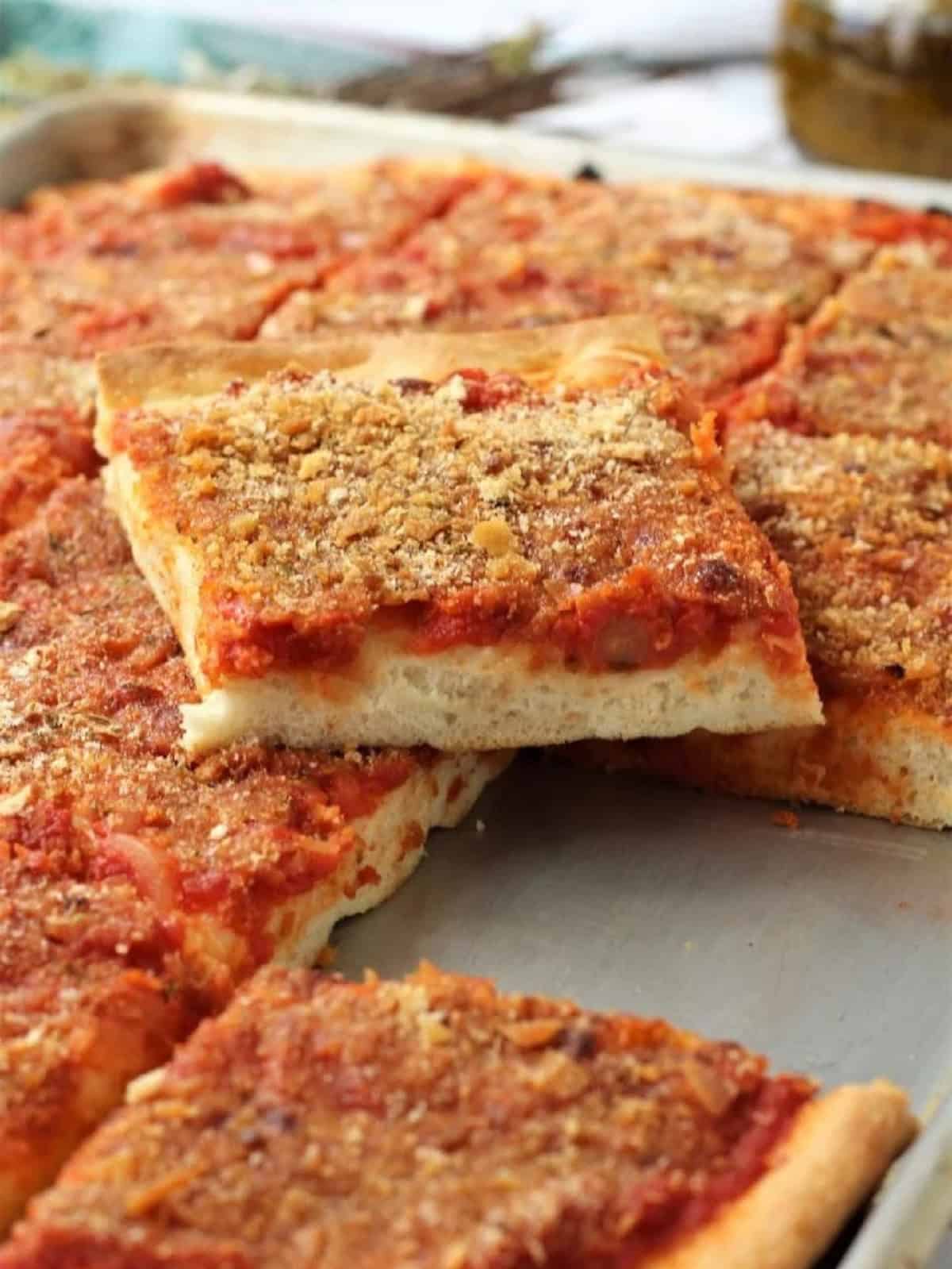 Sicilian sfincione cut into squares on baking sheet.