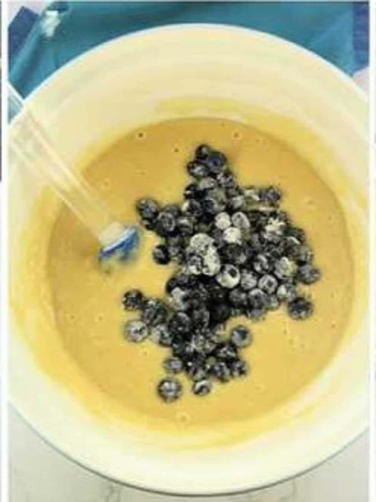 Blueberries stirred into olive oil cake batter in large bowl.