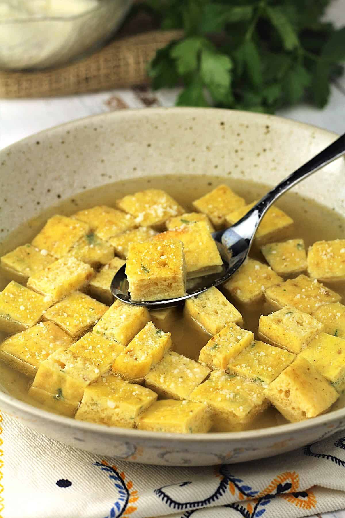 Bowl of frittata soup (zuppa imperiale) being spooned.