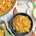 Bowl of pasta with potatoes next to pot with pasta.