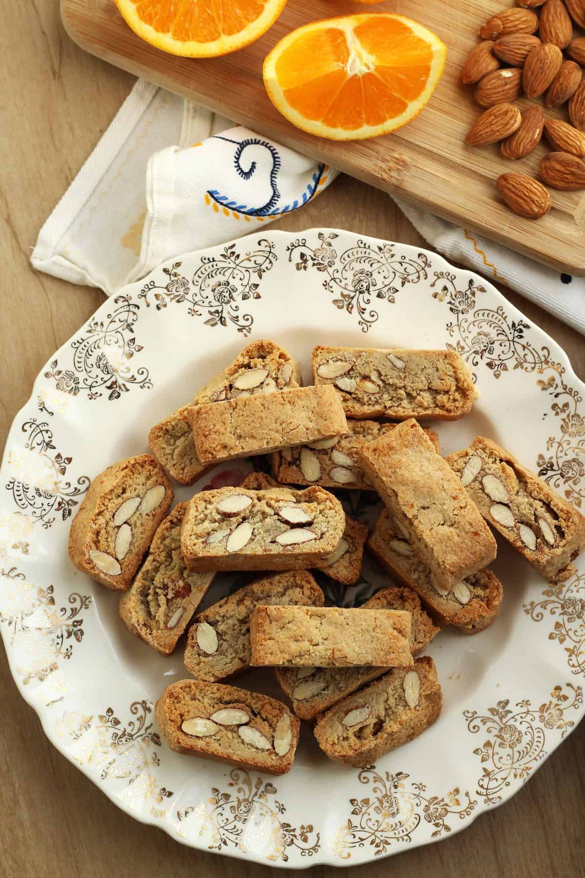 Sicilian quaresimali biscotti with almonds on plate surrounded by orange wedges and almonds.