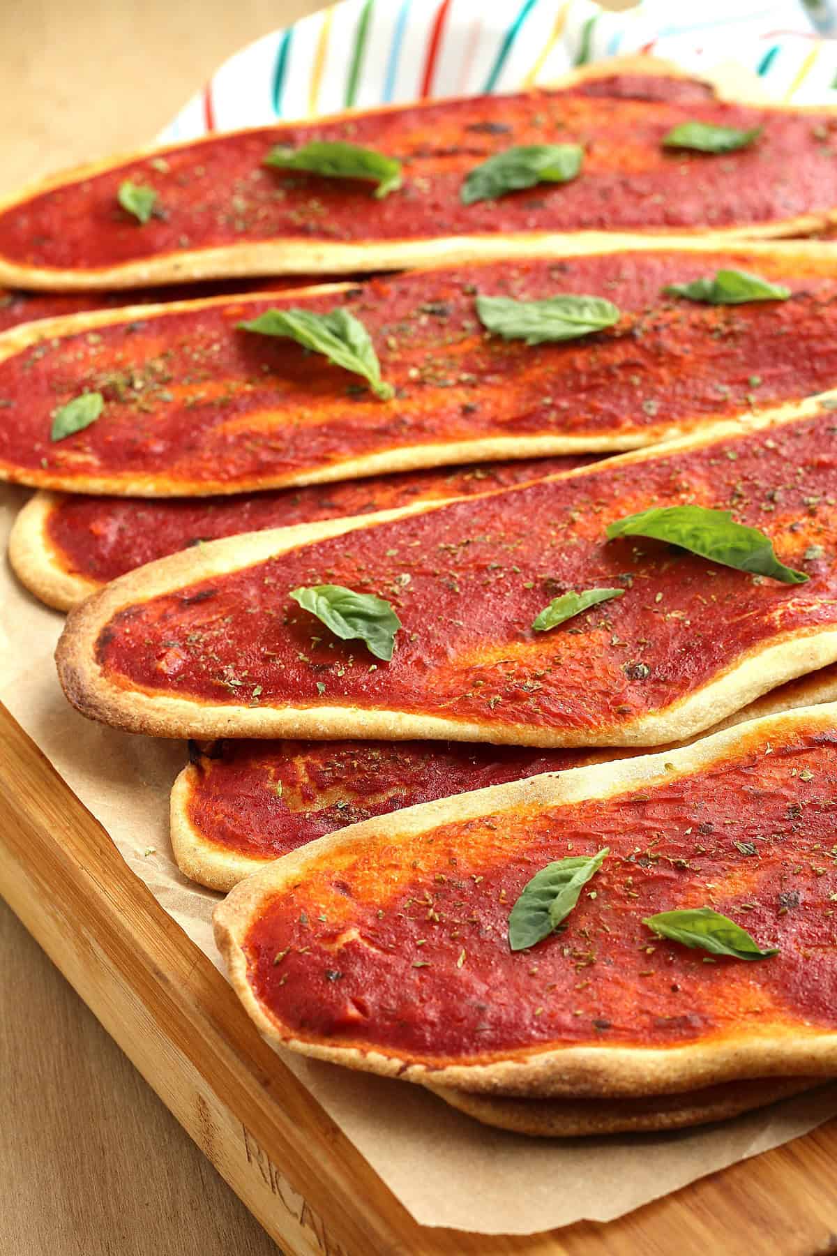 Crisp no yeast pizzas layered on wood board.