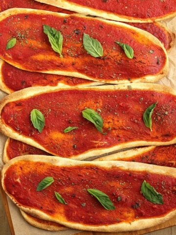 No yeast pizza tongues with tomato sauce layered on wood board.