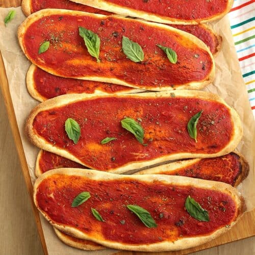 No yeast pizza tongues with tomato sauce layered on wood board.
