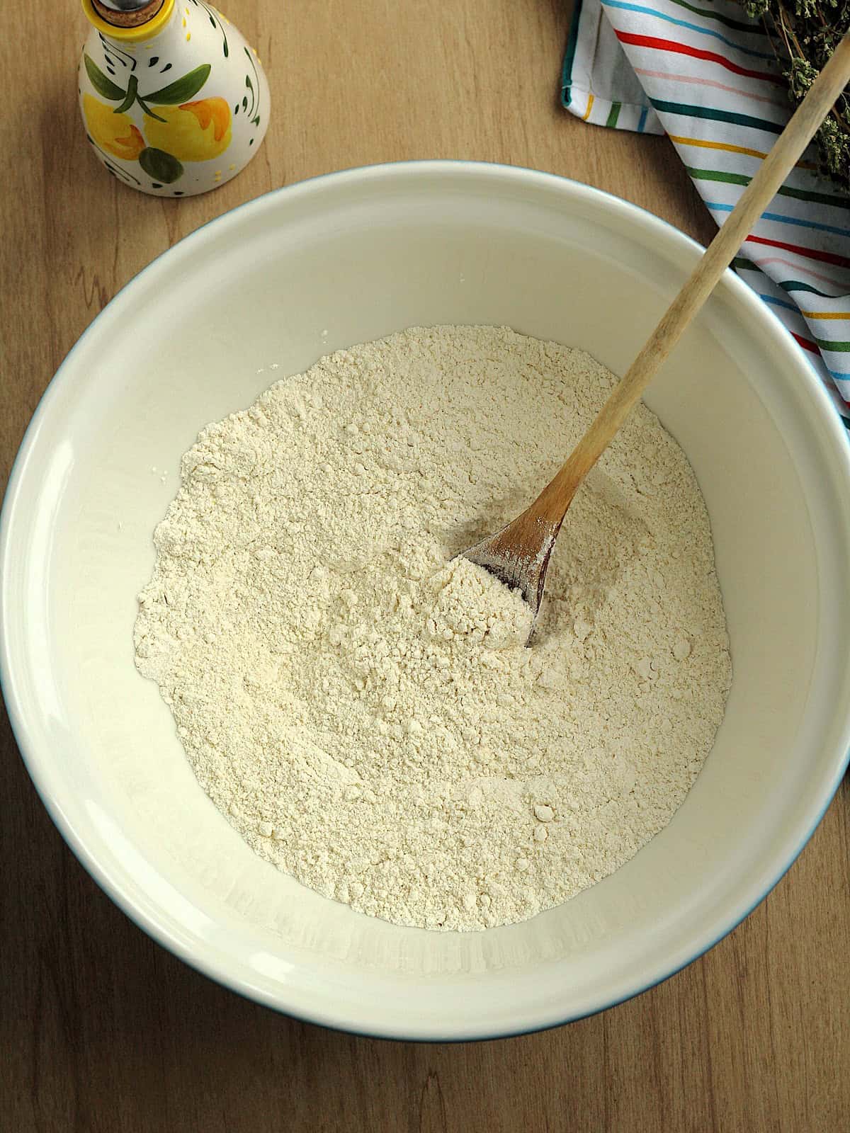 Bowl with flour, semolina and salt stirred together with wooden spoon.