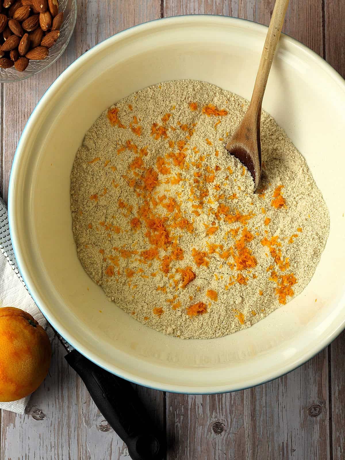 Grated orange zest stirred into almond flour mixture for lenten almond cookies.