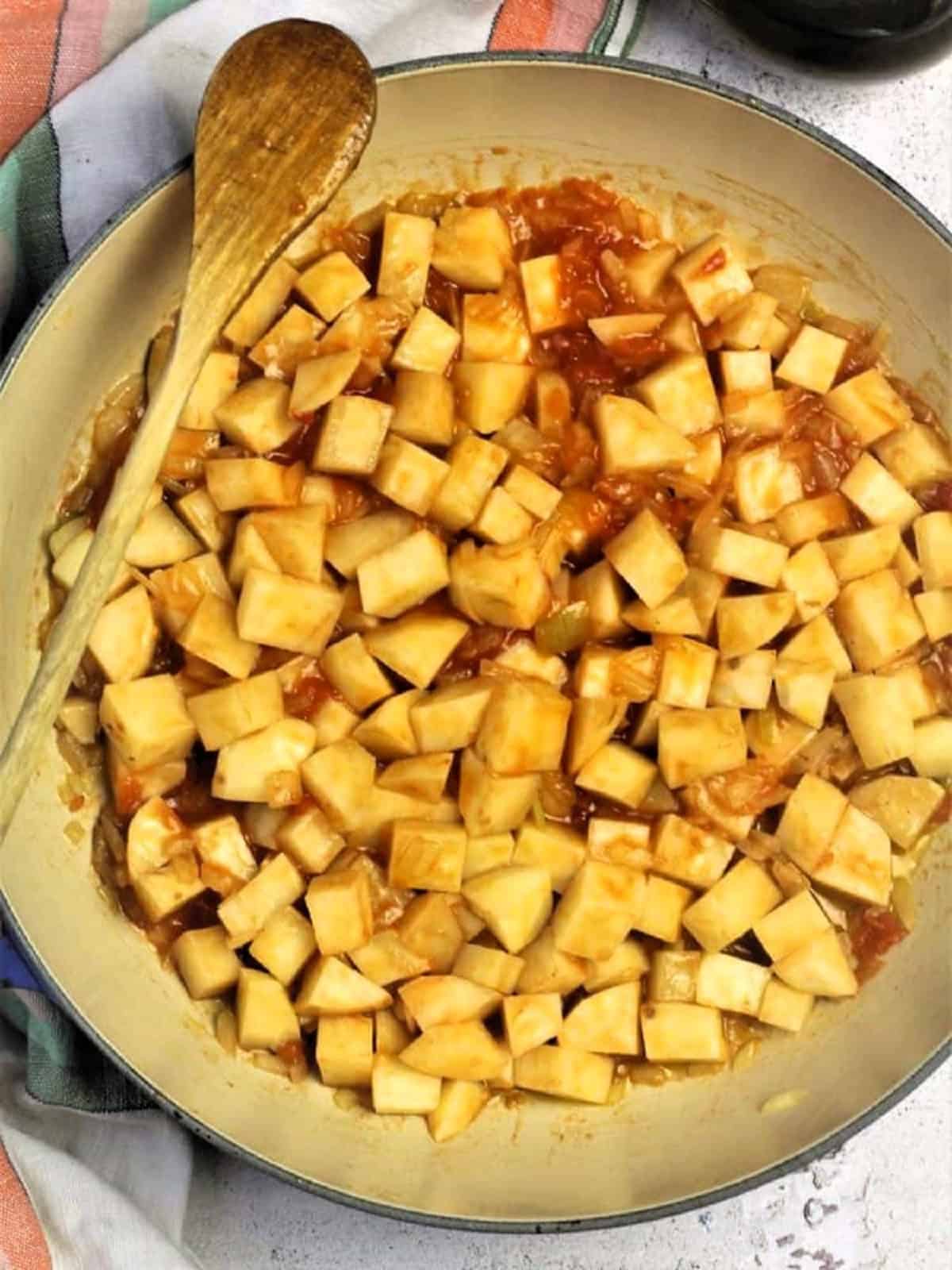 Tomato purée stirred into pan with diced onions and potatoes.