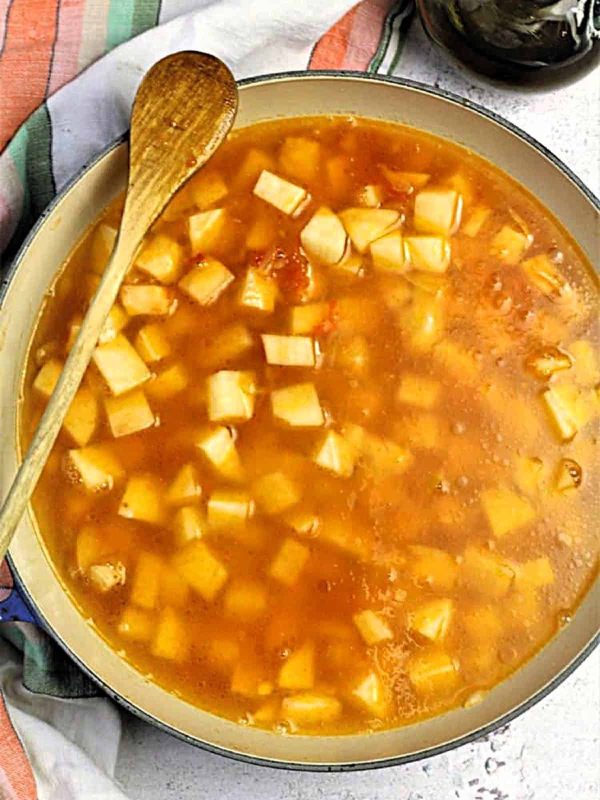 Water stirred into pan with potatoes, onions and tomatoes for pasta with potatoes recipe.
