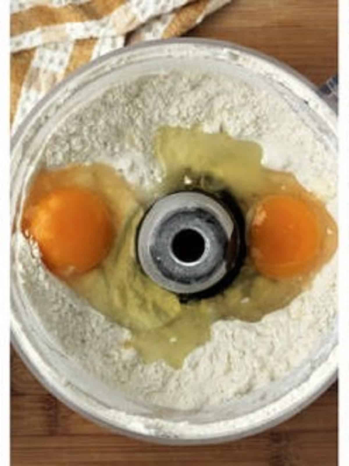 Eggs added to flour in food processor bowl for ricotta pie dough.