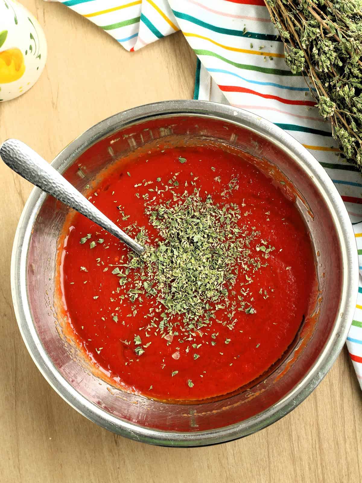 Tomato passata in bowl with oregano stirred in.