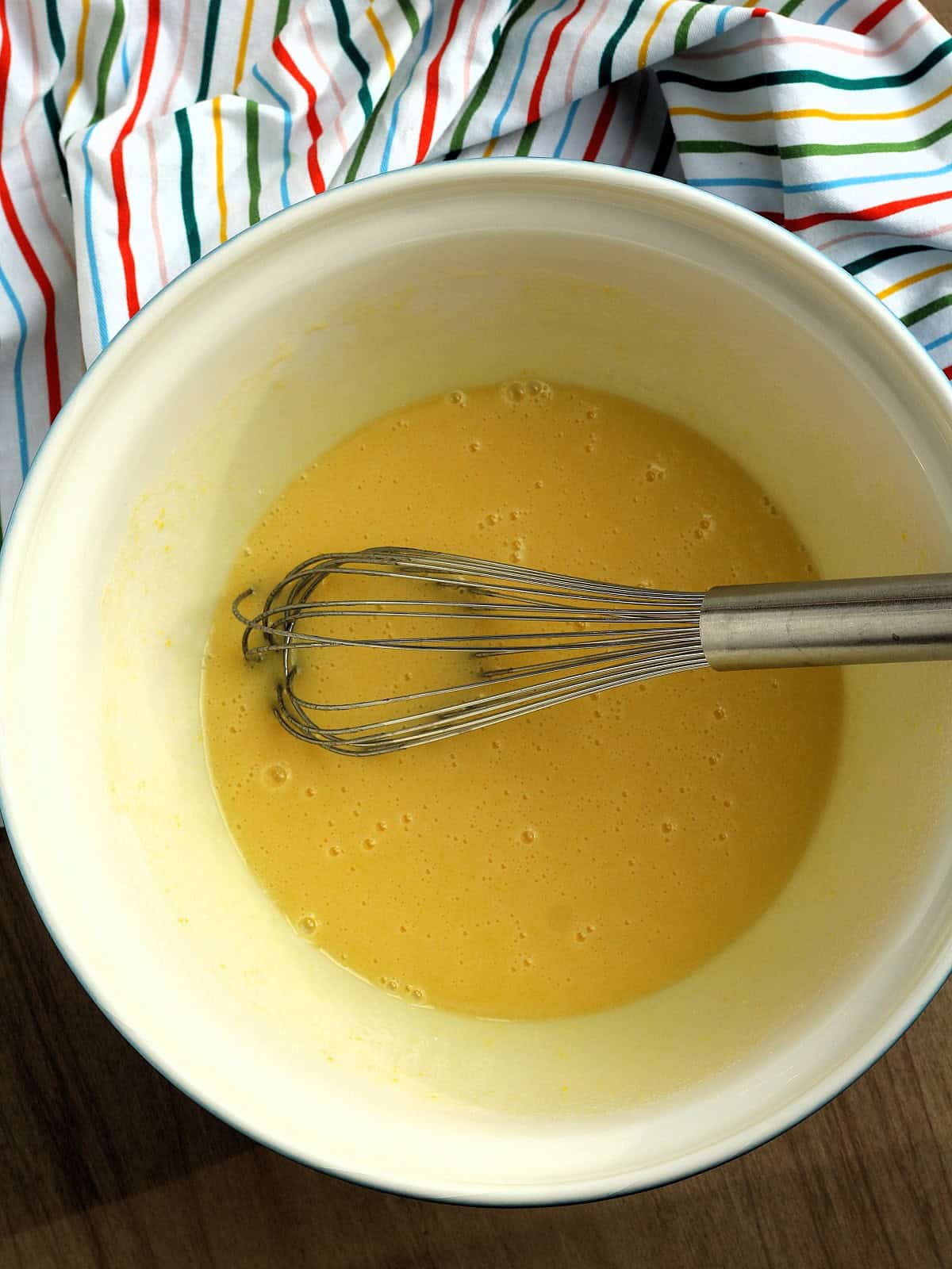 Sugar, eggs and oil whisked together in bowl for whole orange cake.