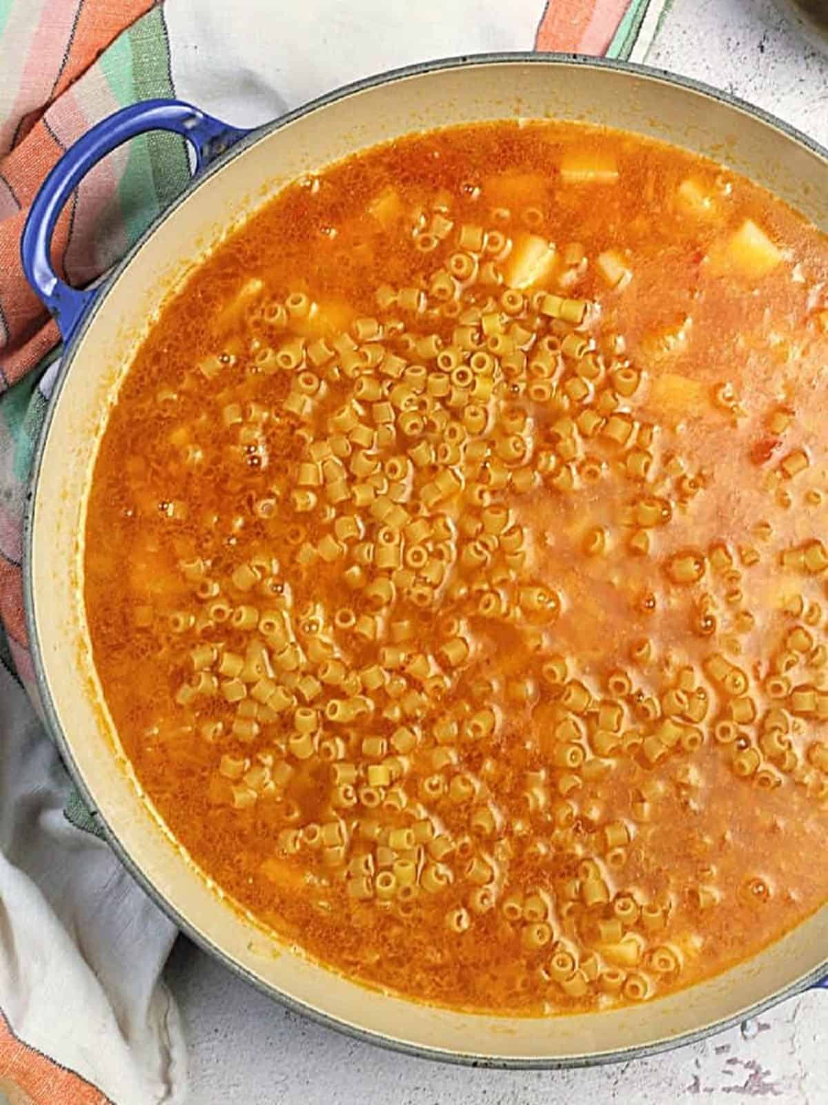 Pasta added to pan with potatoes and tomato purée for pasta e patate recipe.