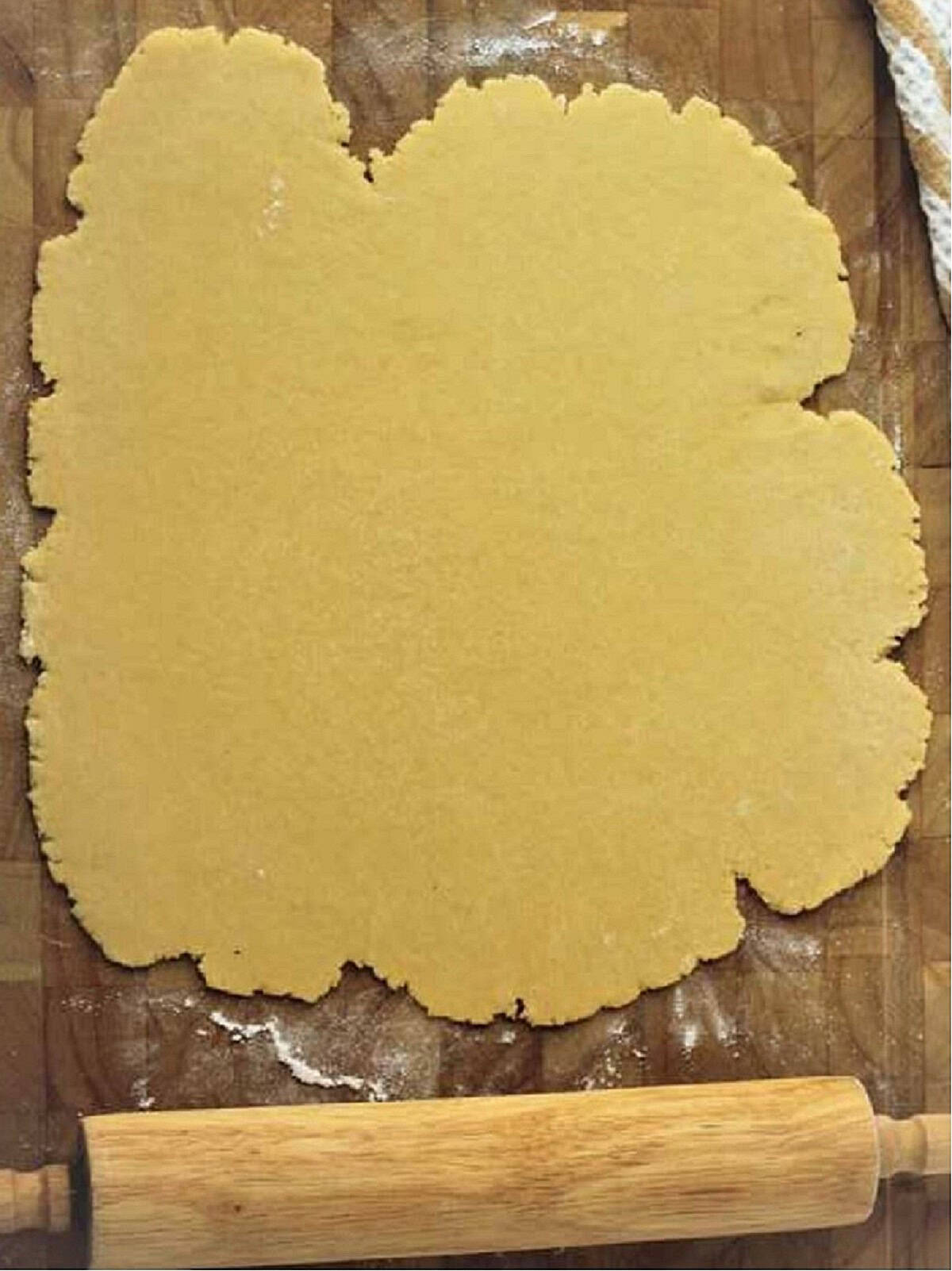 Flattened ricotta pie dough with rolling pin.