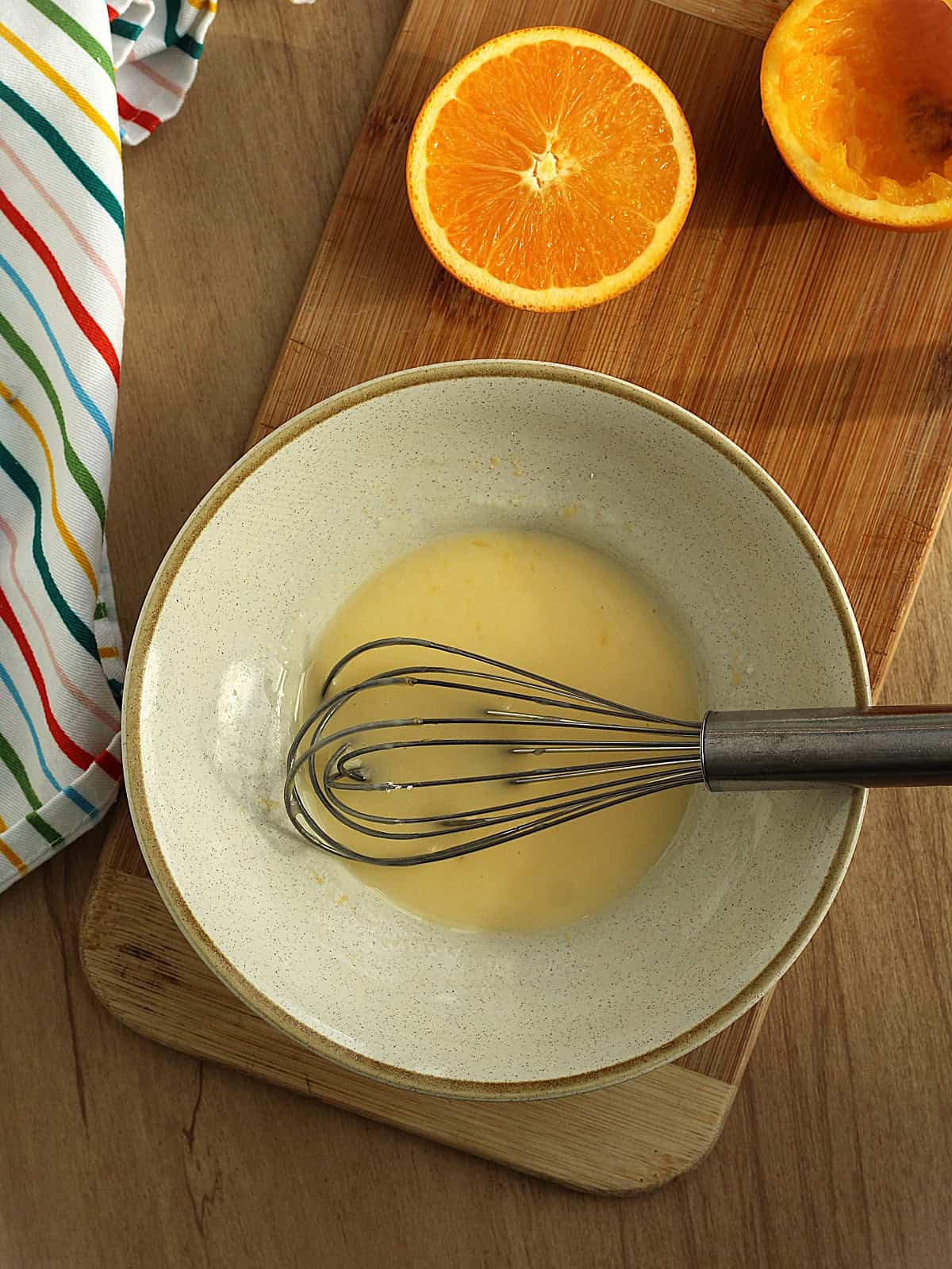 Orange glaze with orange juice and powdered sugar whisked in bowl.