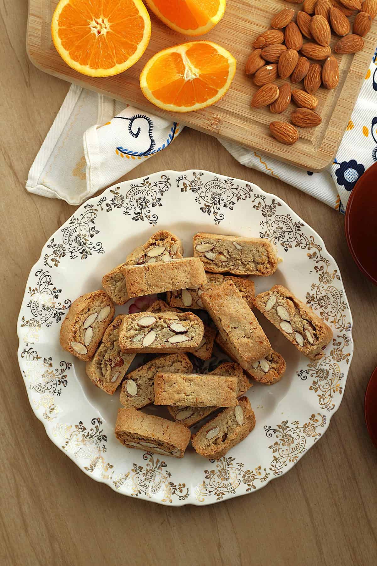Plate filled with quaresimali Sicilian lenten cookies next to orange wedges and almonds.