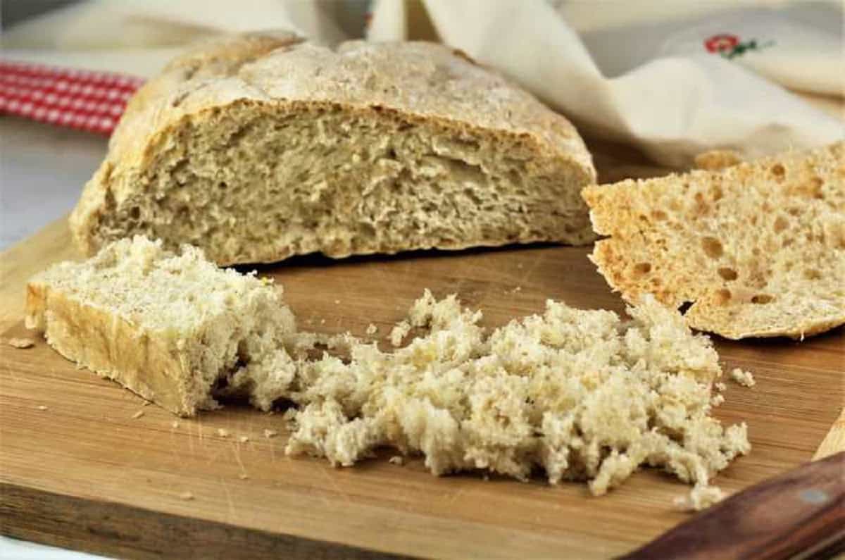 Loaf of Italian bread with crust cut off and hand torn into small pieces for meatball recipe.
