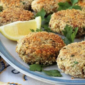 Baked potato tuna patties plated with lemon wedges and parsley sprigs.