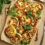 Savoury ricotta cheese fritters piled on wood serving board with sprigs of parsley.