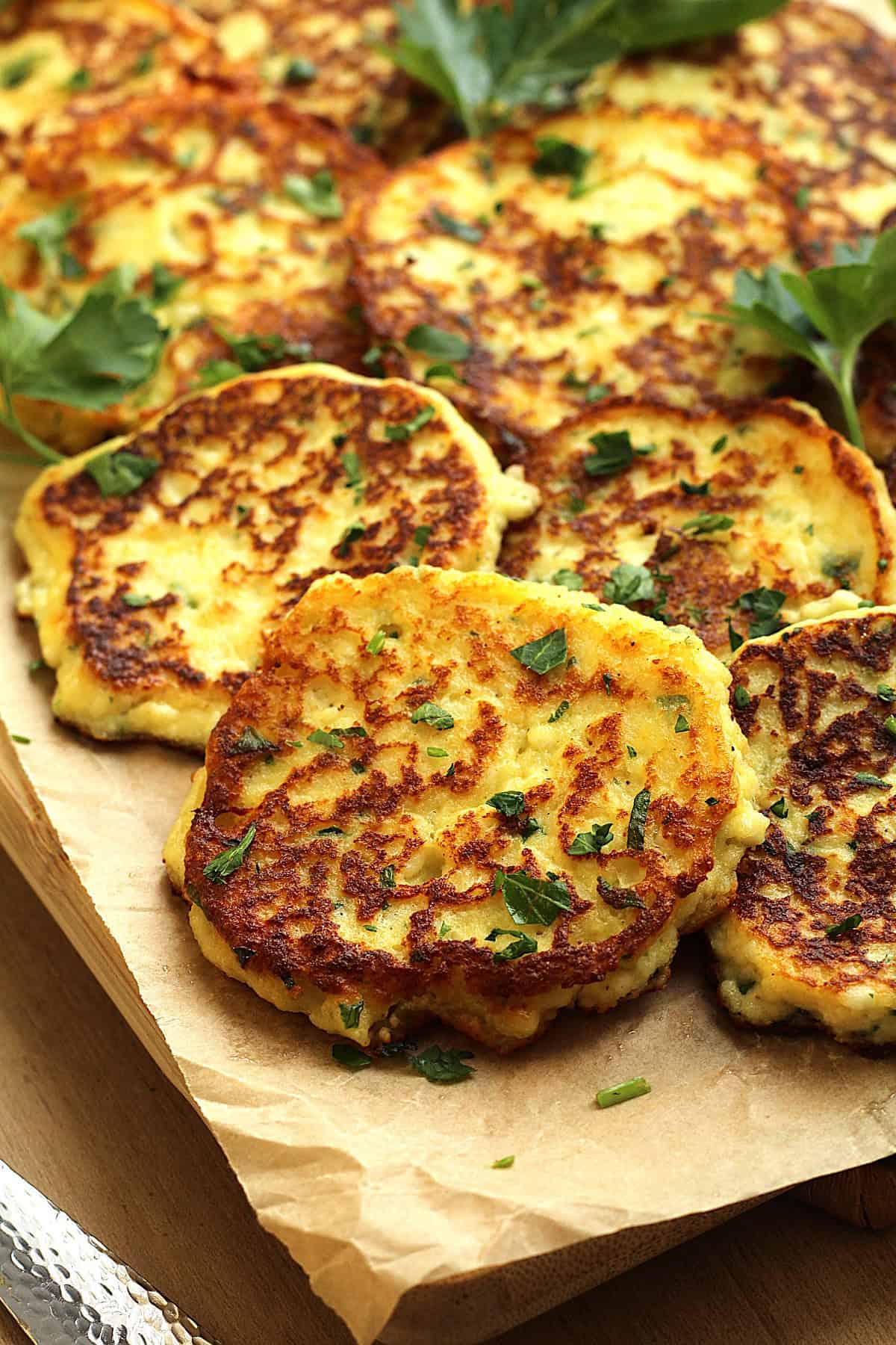 Italian ricotta fritters on parchment paper with a few parsley sprigs.