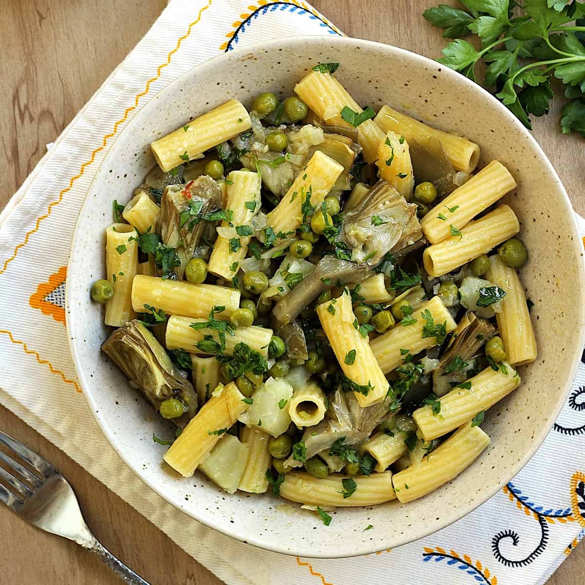 Bowl of artichoke pasta with peas and potatoes.