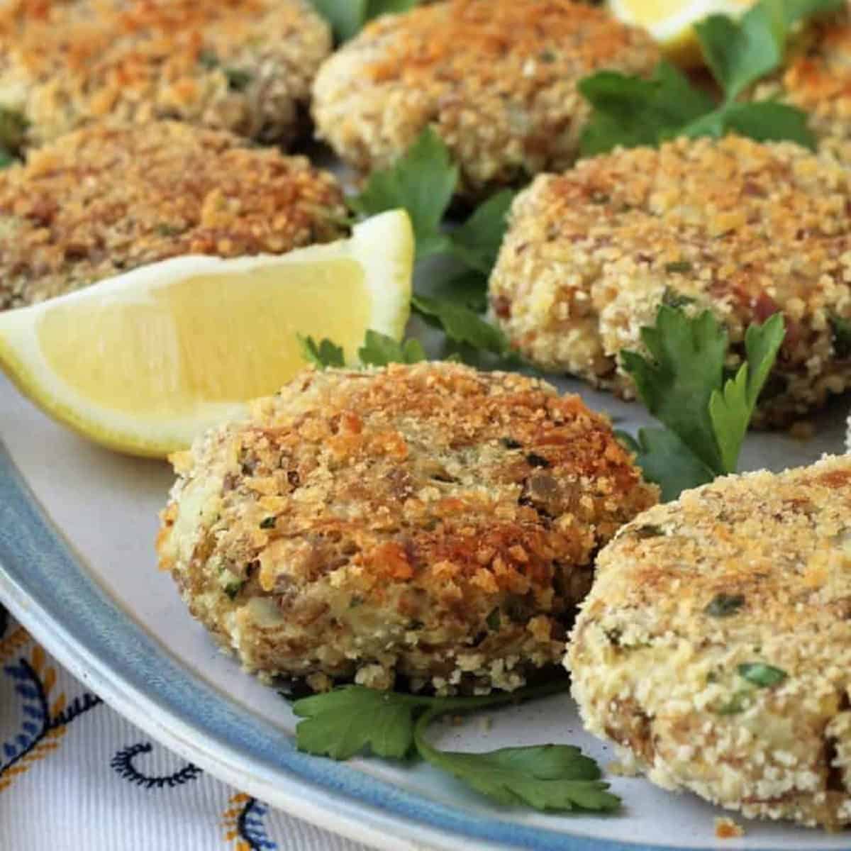 Tuna potato patties plated with lemon wedges.