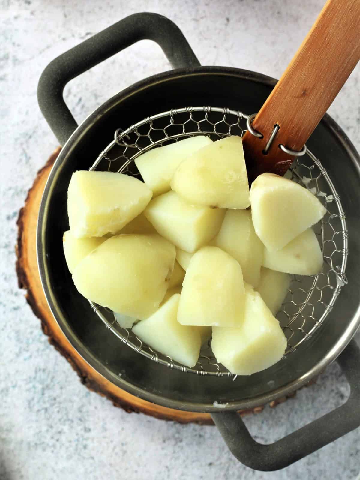 Boiled potato cubes scooped from ot with a spider.