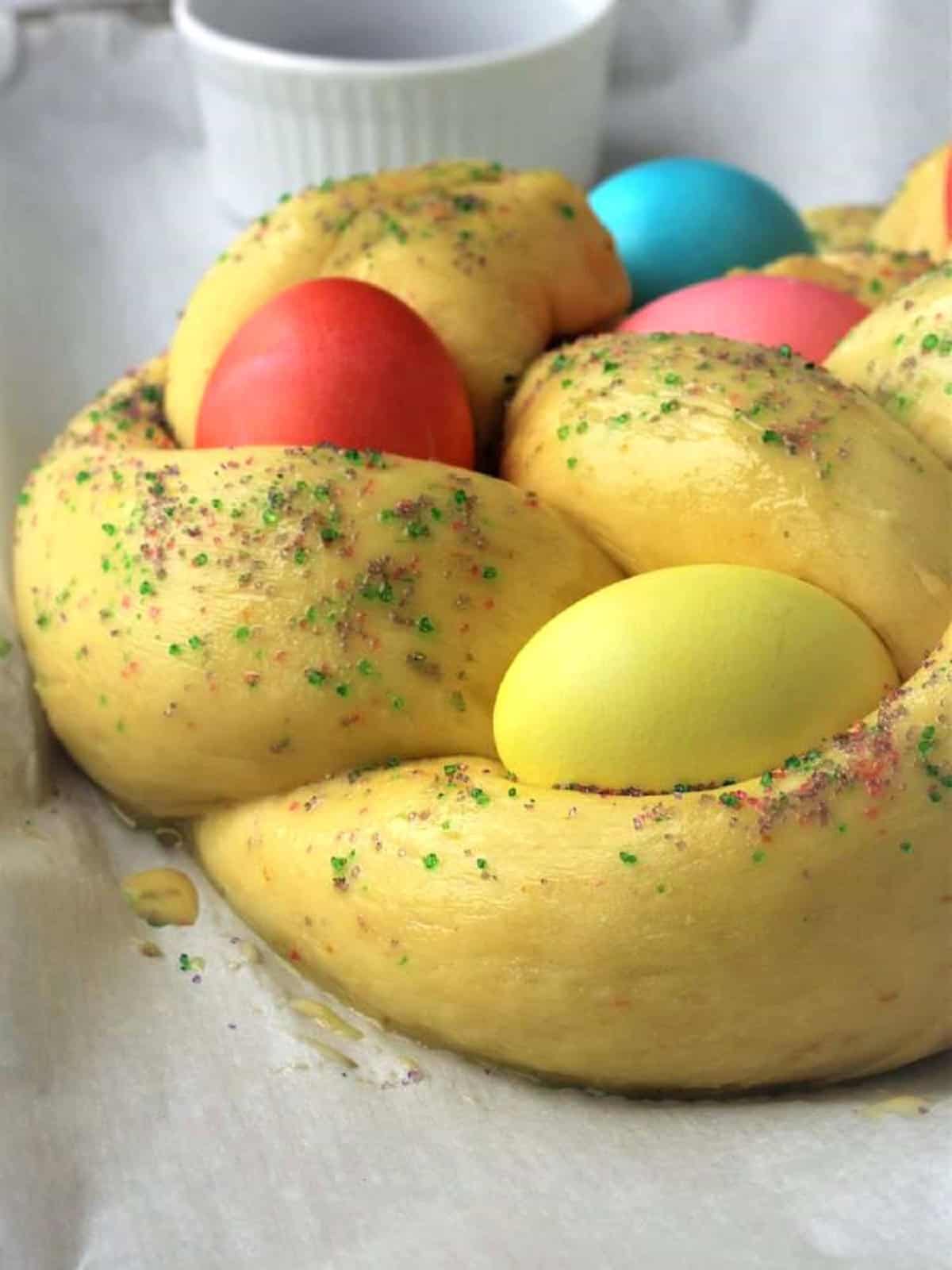 Braided Easter bread with colored eggs brushed with egg wash.
