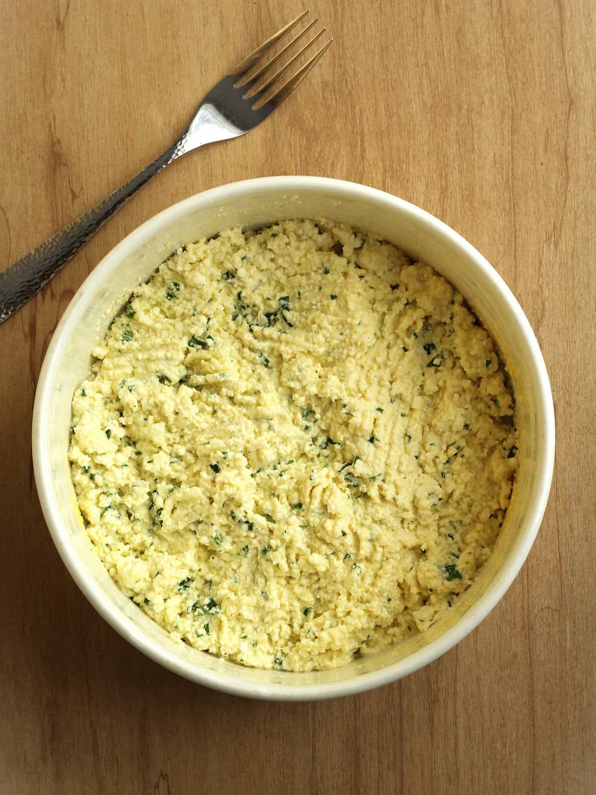 Ricotta cheese fritter mixture stirred in bowl.
