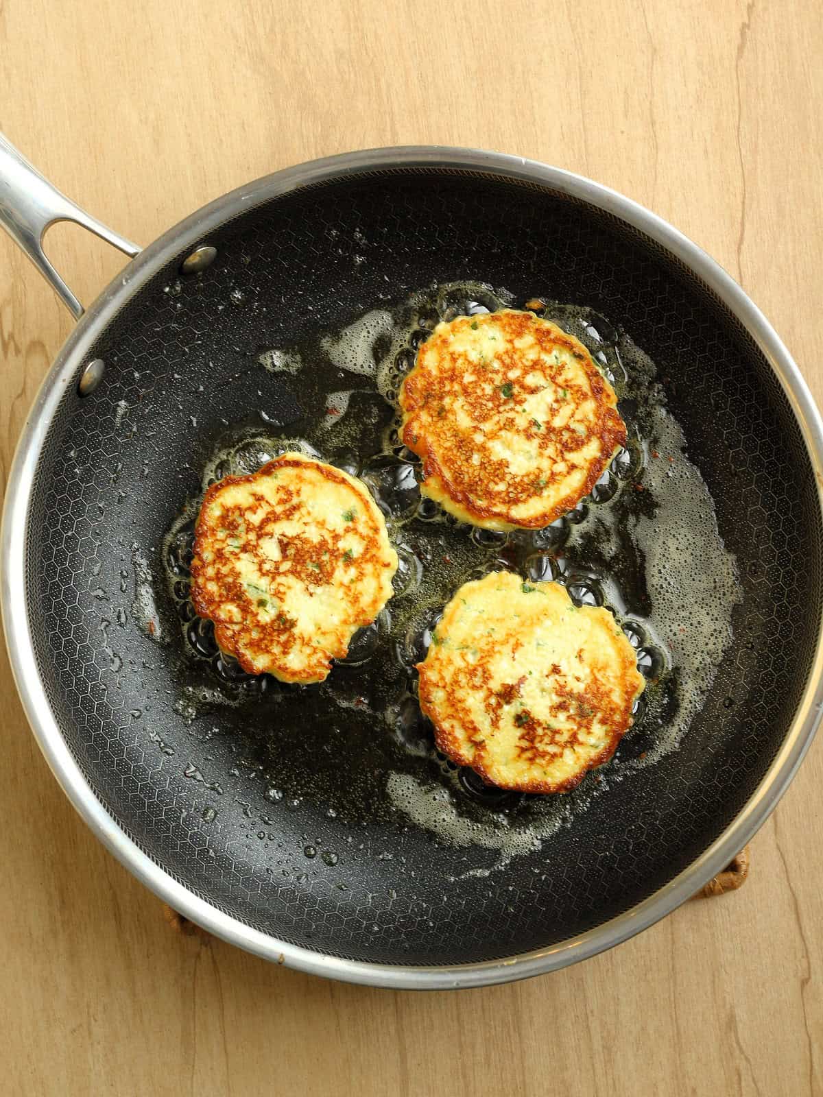 Golden brown fried ricotta cheese fritters in skillet.
