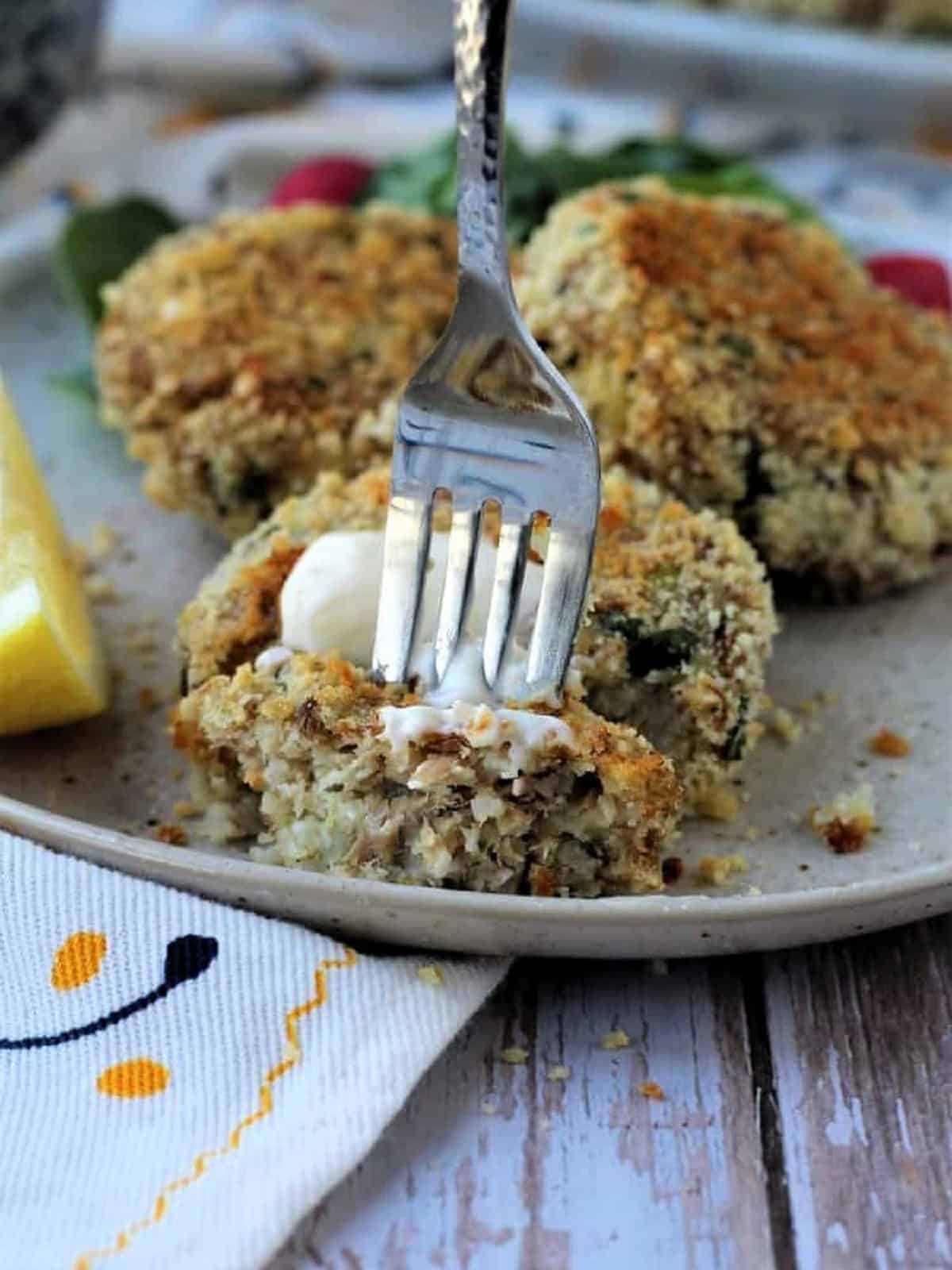 Fork cutting into tuna potato patties topped with aioli