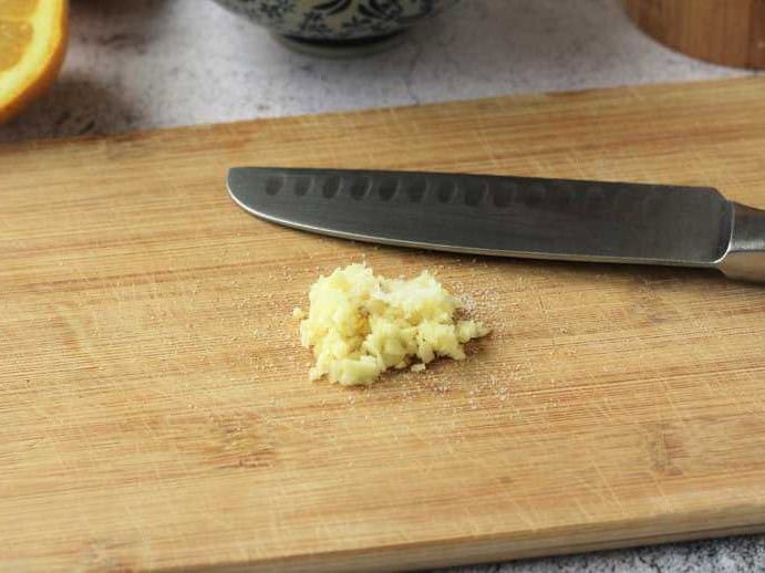 Minced garlic on cutting board with knife.