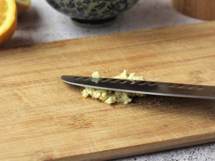 Mashed garlic on cutting board for aioli sauce.