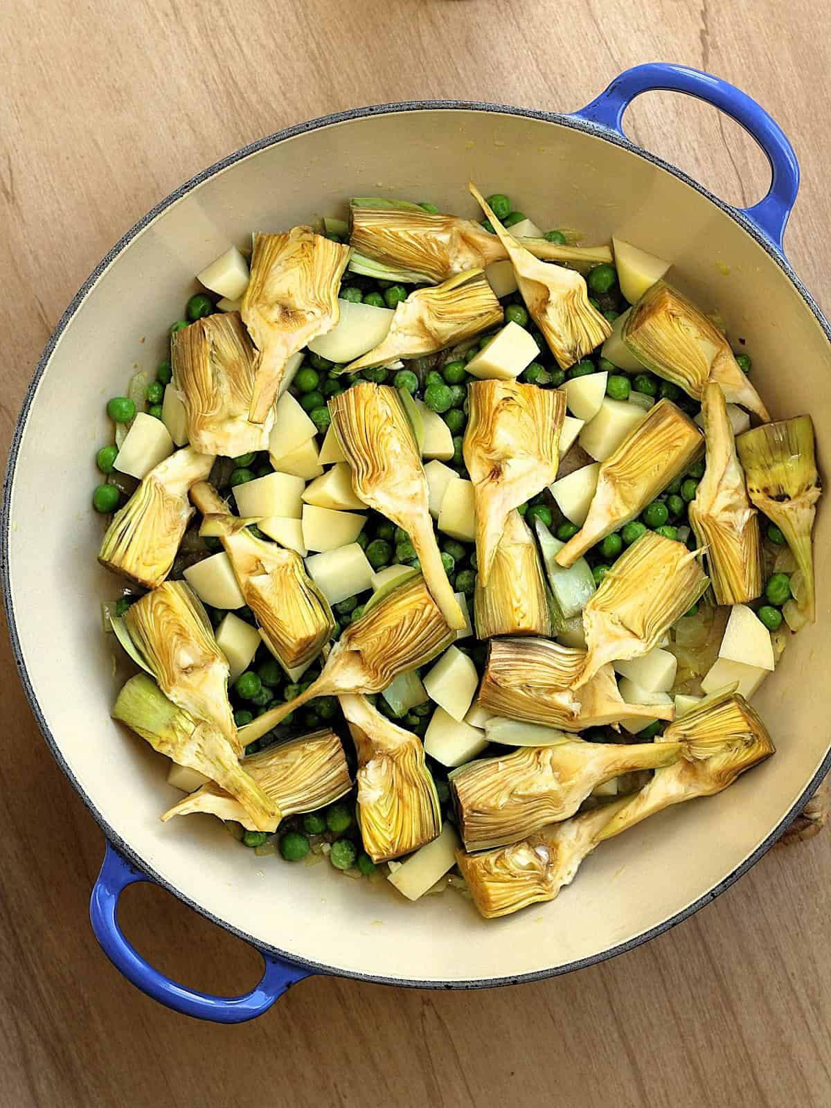 Artichoke quarters, peas and cubed potato added to skillet for artichoke pasta sauce.