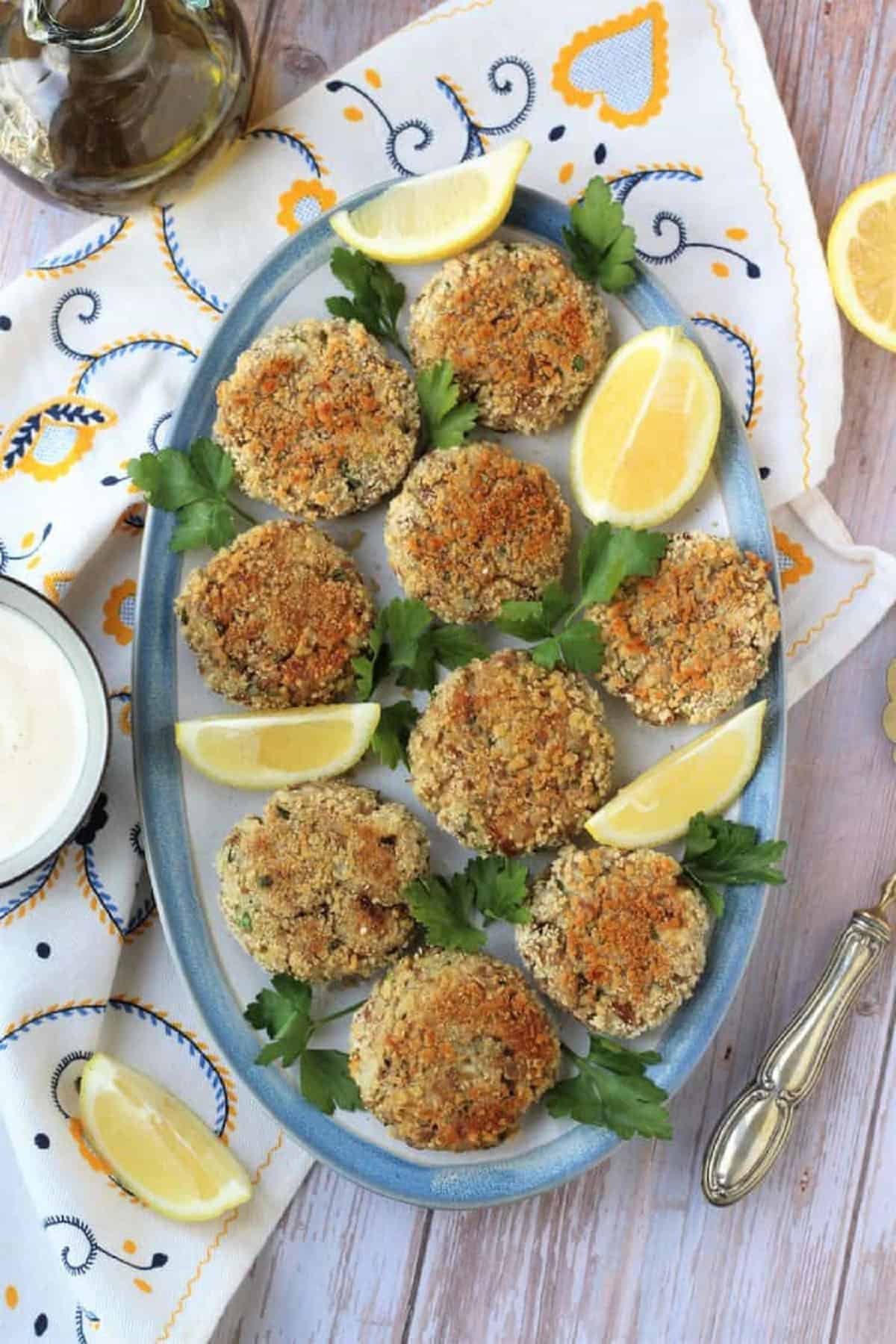 Baked tuna potato patties plated with lemon wedges and parsley sprigs.