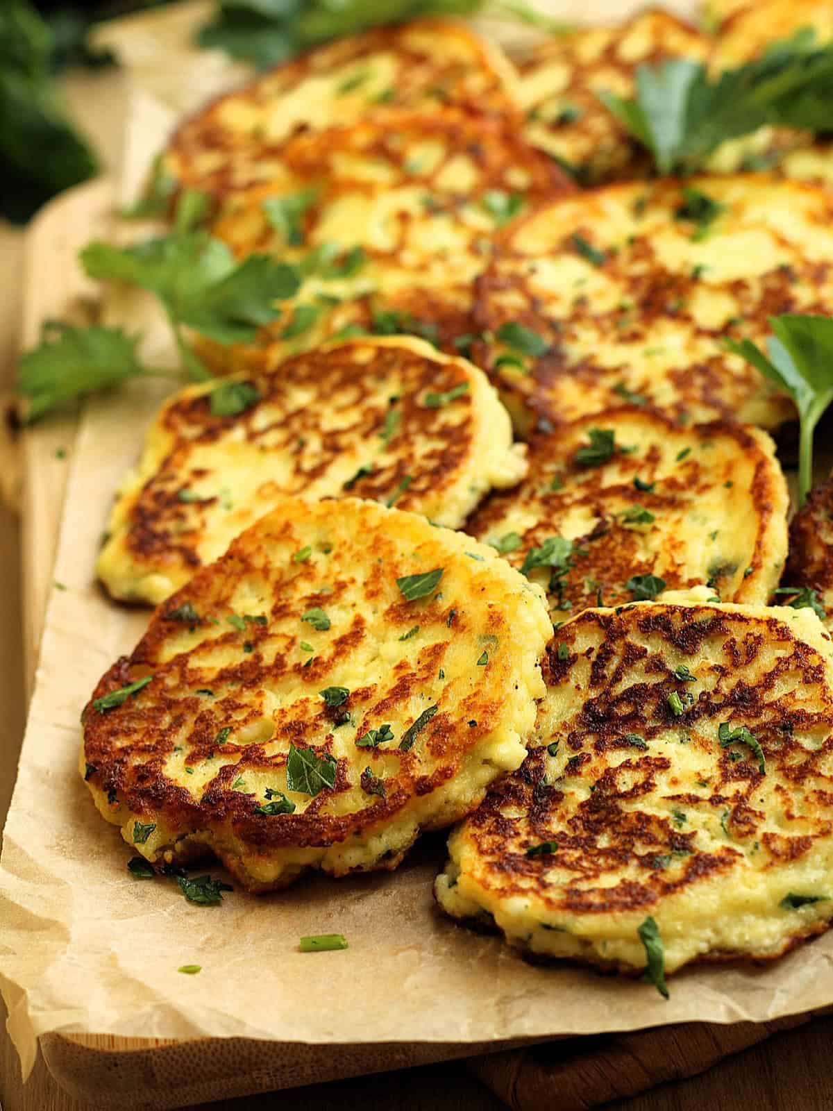 Savoury ricotta cheese fritters on wood board with parsley sprigs.